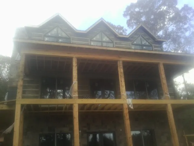 Dormers and porch framing on a large log home under construction — Roof Coating work by our crew in North Brookfield