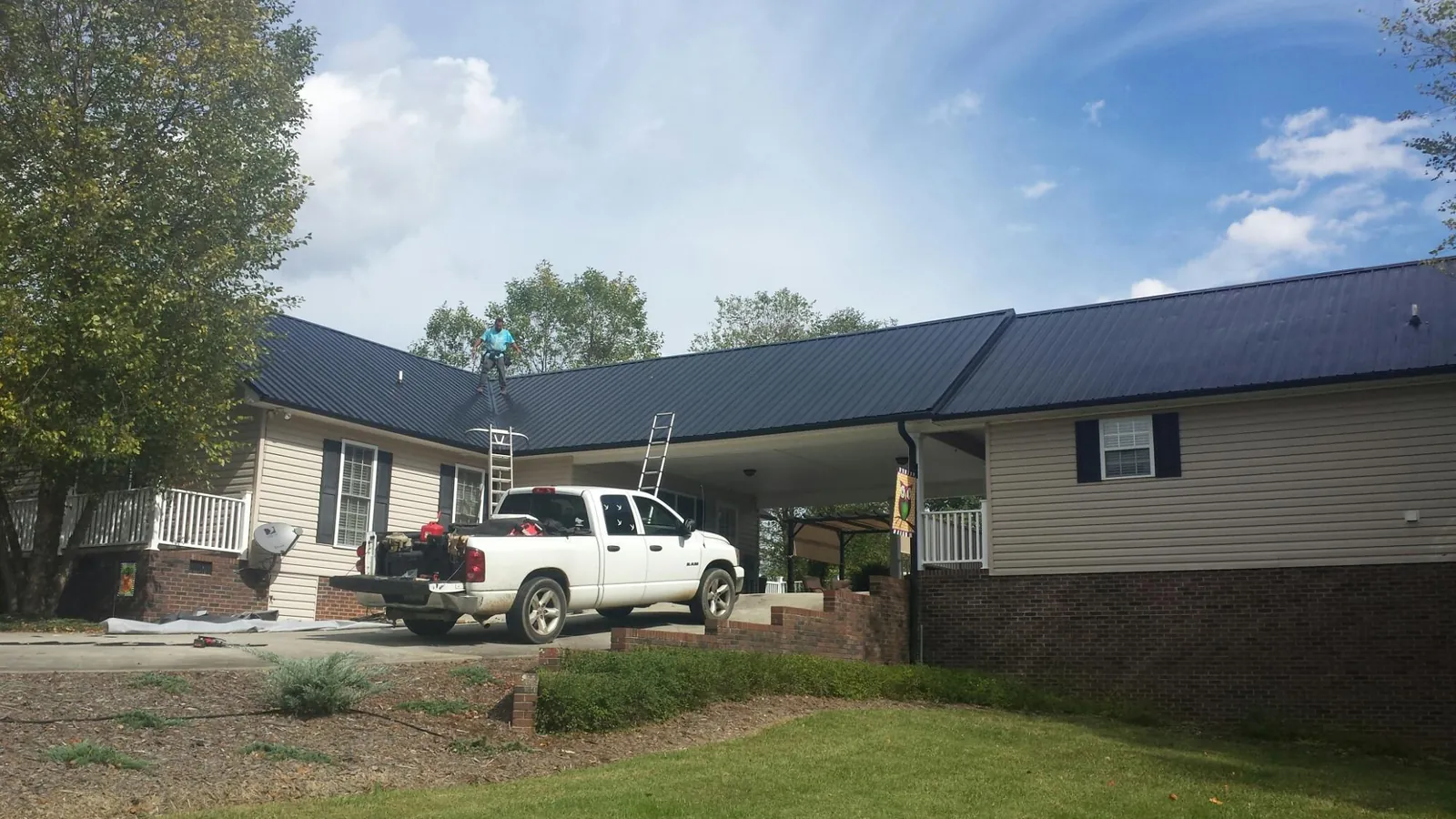 Black metal roof over a home and attached breezeway with ladders set in North Brookfield